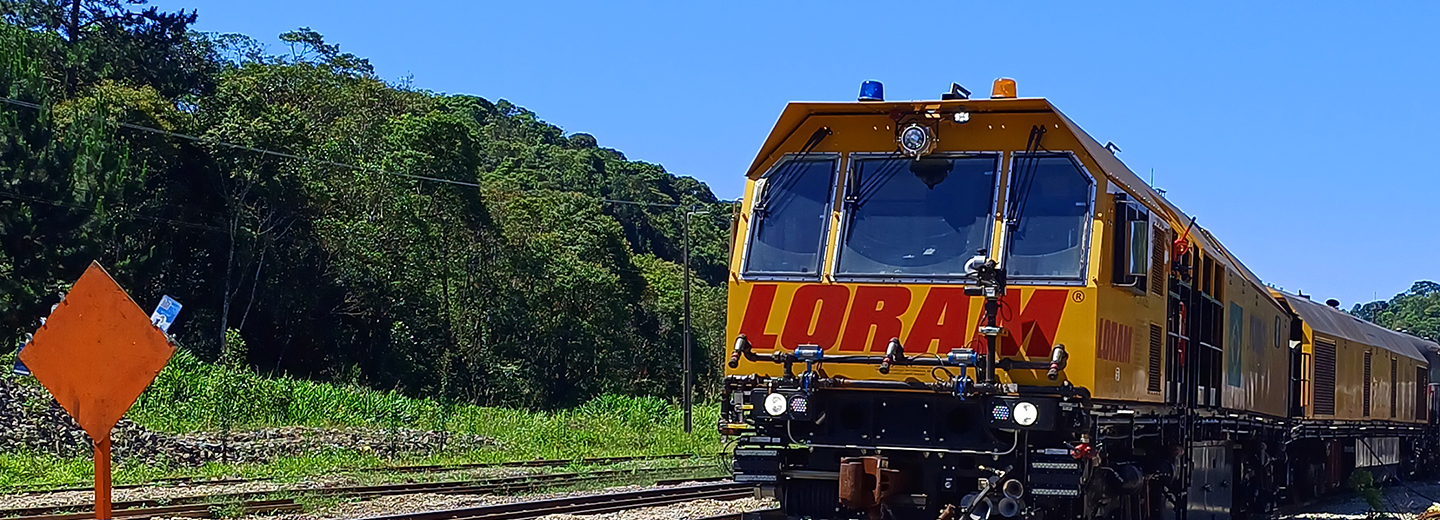 A yellow train on train tracks with trees and sky in the background