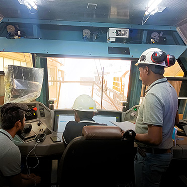 Three men look at a screen at a dashboard.